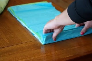 Stacked sheets of tissue paper being folded into a 1 inch strip