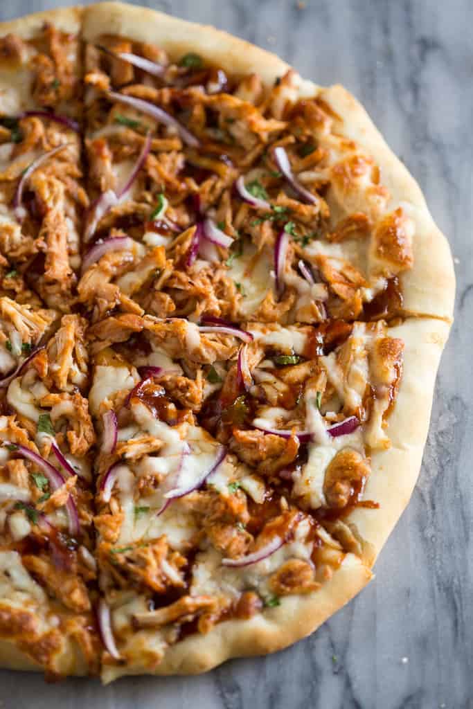 Close-up photo of half of a bbq chicken pizza, cut into slices. 