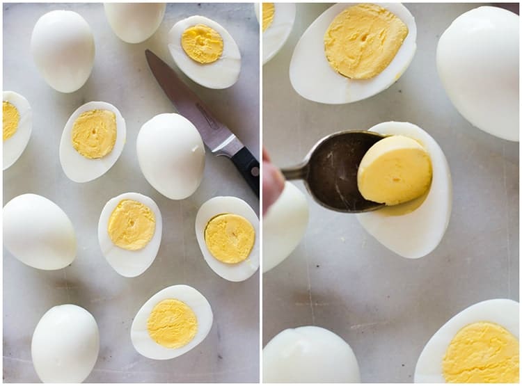 Cooked eggs, cut in half and a spoon removing the egg yolks to make deviled eggs.