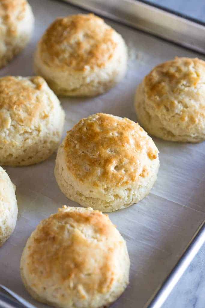 Golden brown buttermilk biscuits on a baking sheet lined with parchment paper.