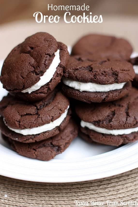 A dozen Homemade Oreo Cookies with cream cheese filling stacked on a white plate.