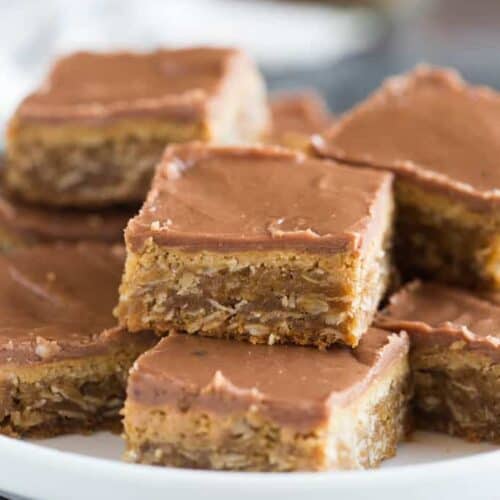 A plate full of the world's BEST peanut butter bars. Thick and chewy, with layers of smooth peanut butter and chocolate frosting.