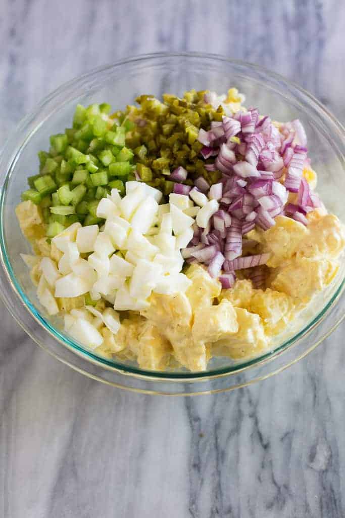 Potato salad ingredients layered in a bowl.