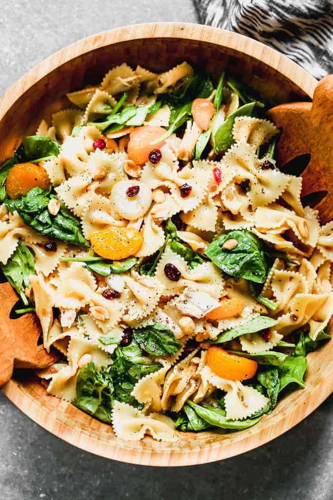 Teriyaki Pasta Salad served in a large wood bowl with wooden tongs.