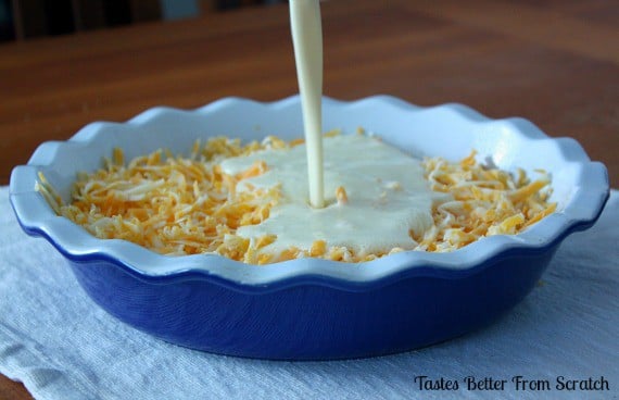 Egg mixture being poured over cheese in pie dish.
