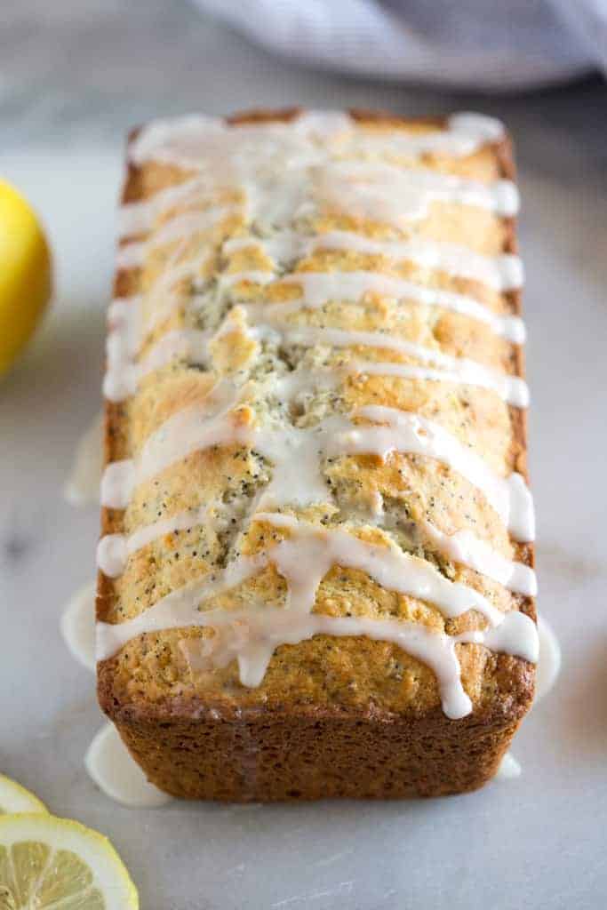 A loaf of lemon poppy seed bread with a glaze drizzled on it.
