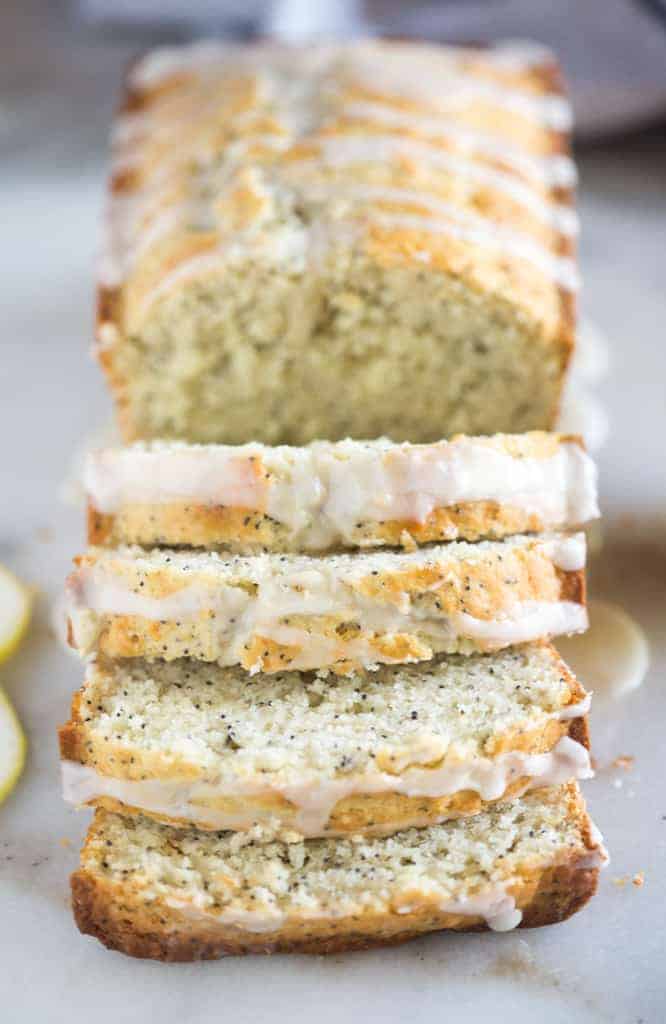 Lemon poppyseed bread with a glaze, and with 4 slices cut and the rest of the loaf whole.