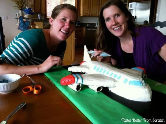 Two girls posing with airplane cake.