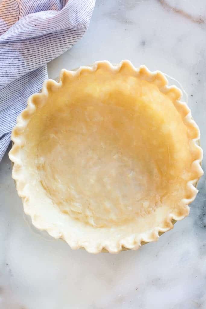 Pie crust with a crimped edge in a pie dish ready to be baked.