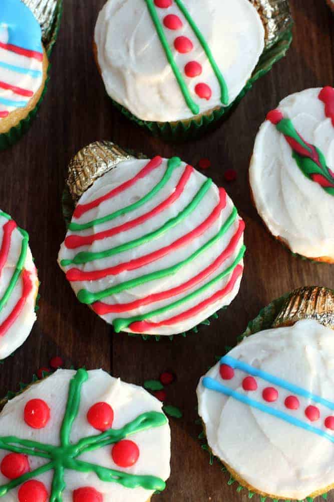A cupcake decorated as an ornament with green and red stripes and a Reese's at the top.
