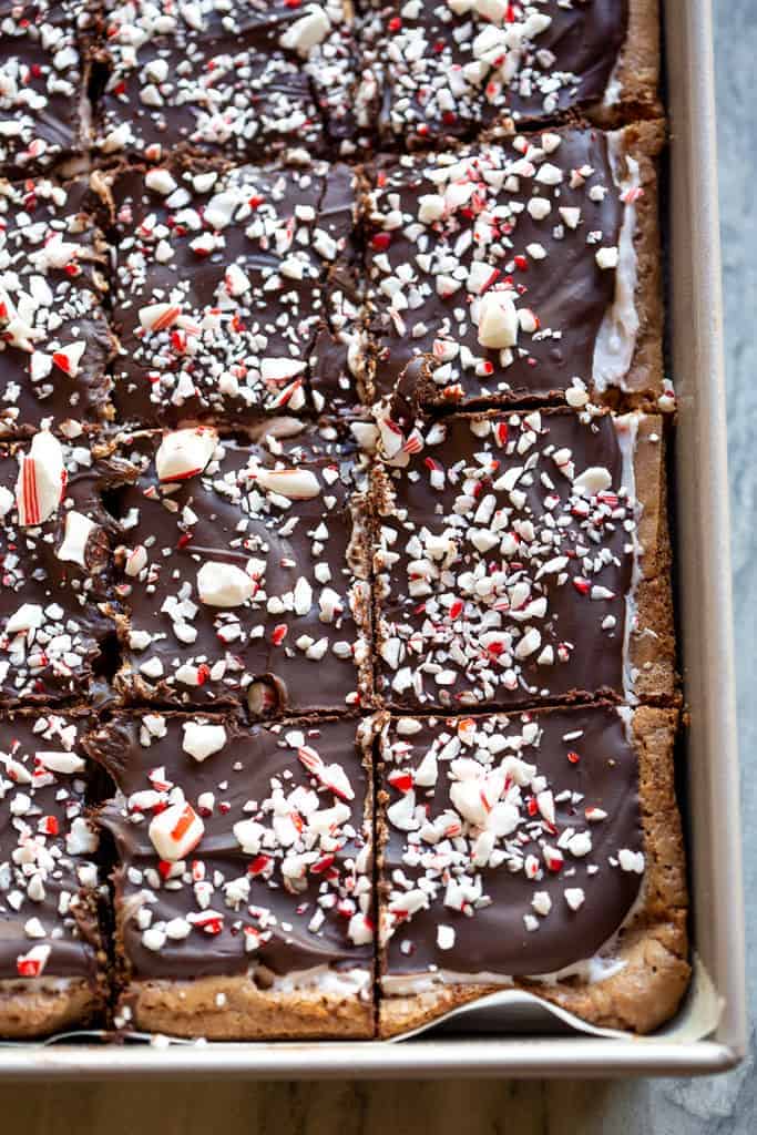 Close-up of the corner of a pan of cut peppermint brownies with crushed candy canes on top.