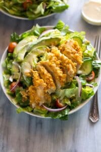 A green salad with cornflake crusted chicken, avocado and honey mustard dressing.