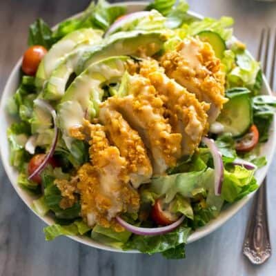 A green salad with cornflake crusted chicken, avocado and honey mustard dressing.