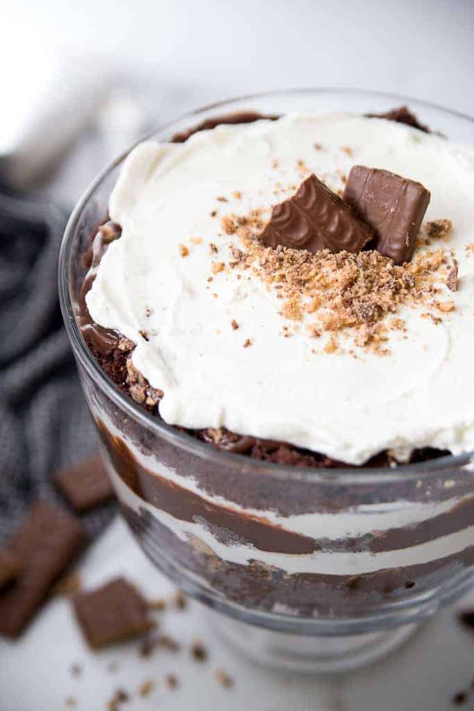 A chocolate trifle with layers of cake, whipped cream and pudding and crushed heath candy bars on the top.