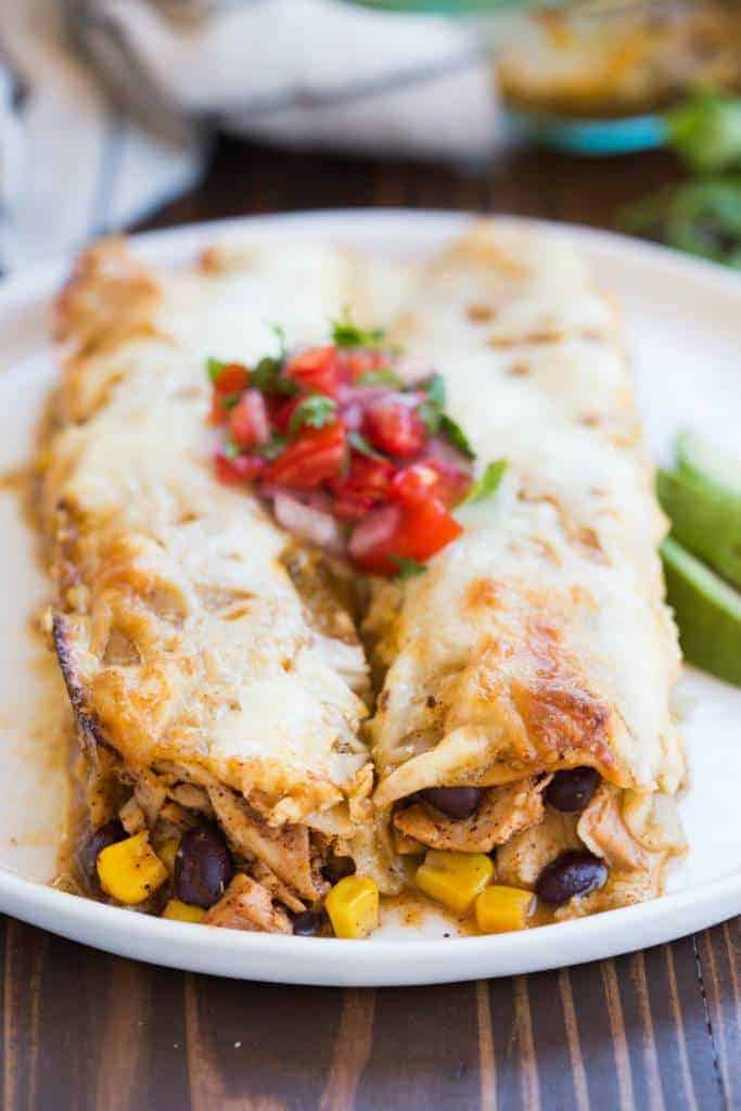 These honey lime chicken enchiladas are one of our favorites! The filling includes marinated Honey lime chicken, black beans, corn, and cheese, rolled in tortillas and smothered in salsa verde. | tastesbetterfromscratch.com
