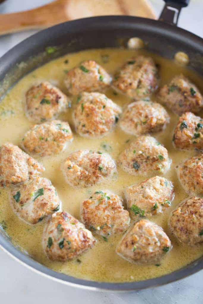 Thai green curry meatballs in a skillet with a coconut milk sauce.