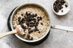 A pot with cooked brown rice pudding with raisins added on top.