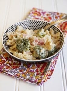 A bowl filled with baked pasta and broccoli with ham.