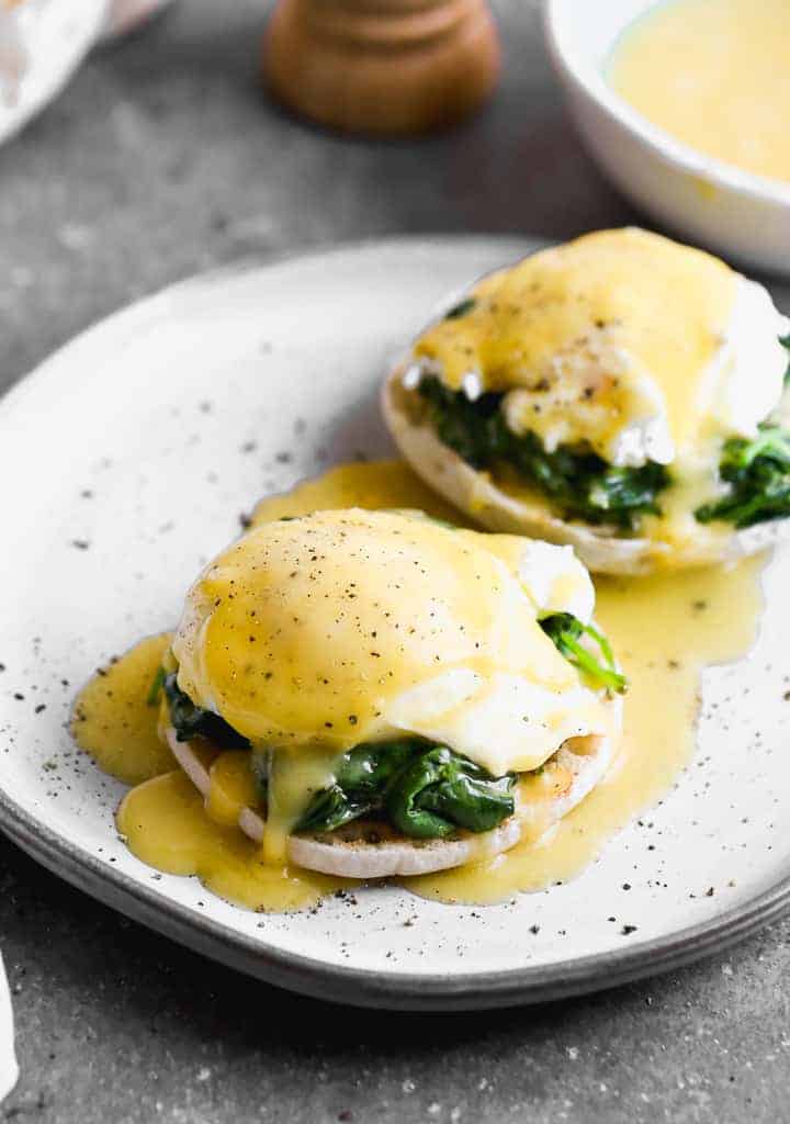 Two eggs florentine on a white plate.