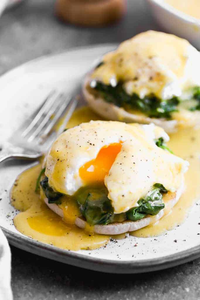 A plate with eggs florentine on it (english muffin topped with spinach, poached egg and hollandaise sauce).