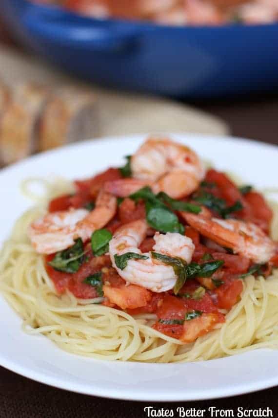 Cappellini Pomodoro on a white plate topped with shrimp. 
