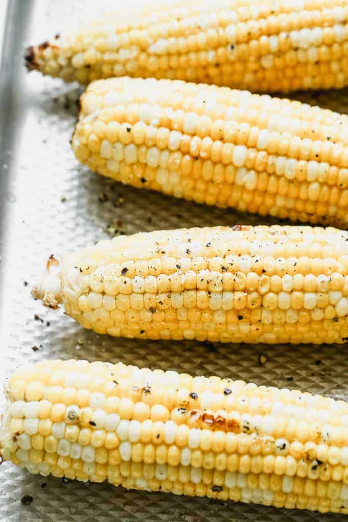 Grilled corn ears on a baking sheet.