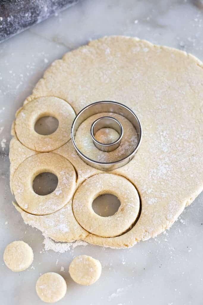 Rolled out homemade donut dough cut into circles using metal round cookie cutters.