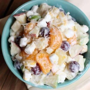 Creamy Fruit Salad Recipe from TastesBetterFromScratch.com - all of my favorite fruits mixed with mini marshamallows and coconut and coated in greek yogurt! A healthy side and delicious!