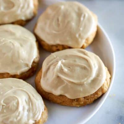 A plate fill of pumpkin cookies with caramel frosting.
