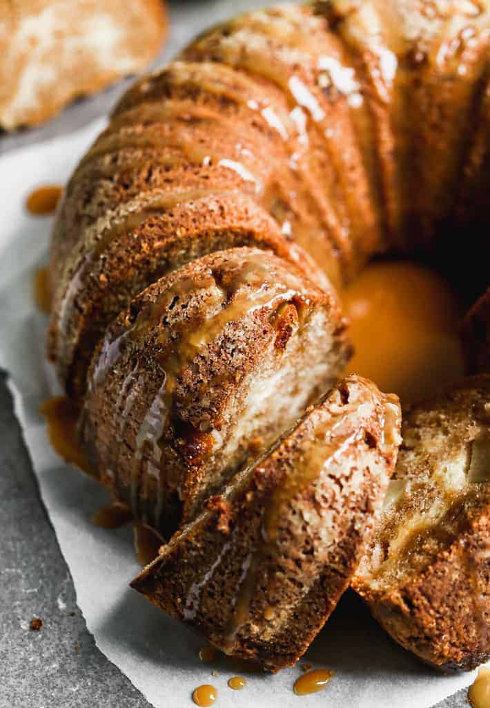 A full apple bundt cake with caramel sauce drizzled on top.