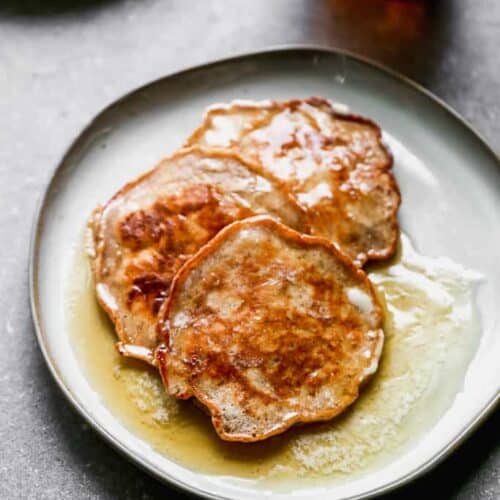 Three Apple Pancakes overlapping on a plate with syrup on top.