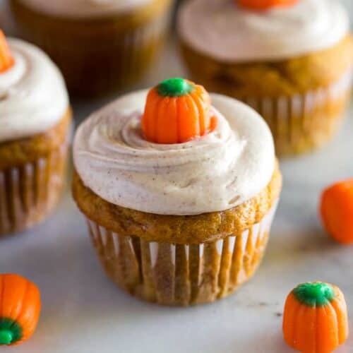 Pumpkin cupcakes with cream cheese frosting and a candy pumpkin on top.