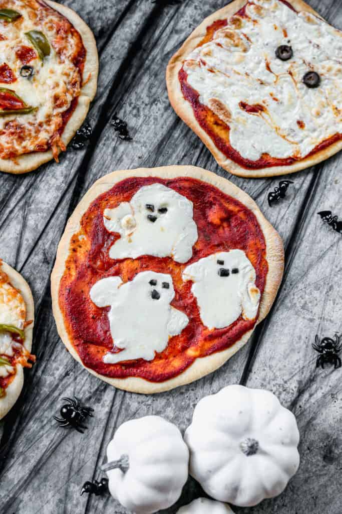 A ghost themed Halloween Pizza made with mozzarella cheese and olives for the toppings.