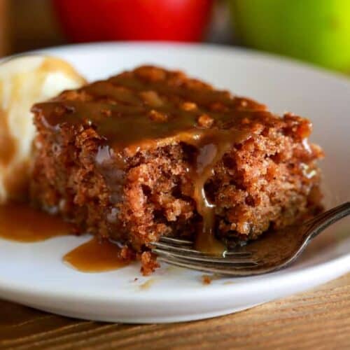 Apple cake made with fresh grated apples, served with caramel sauce drizzled on top and a scoop of ice cream on side.