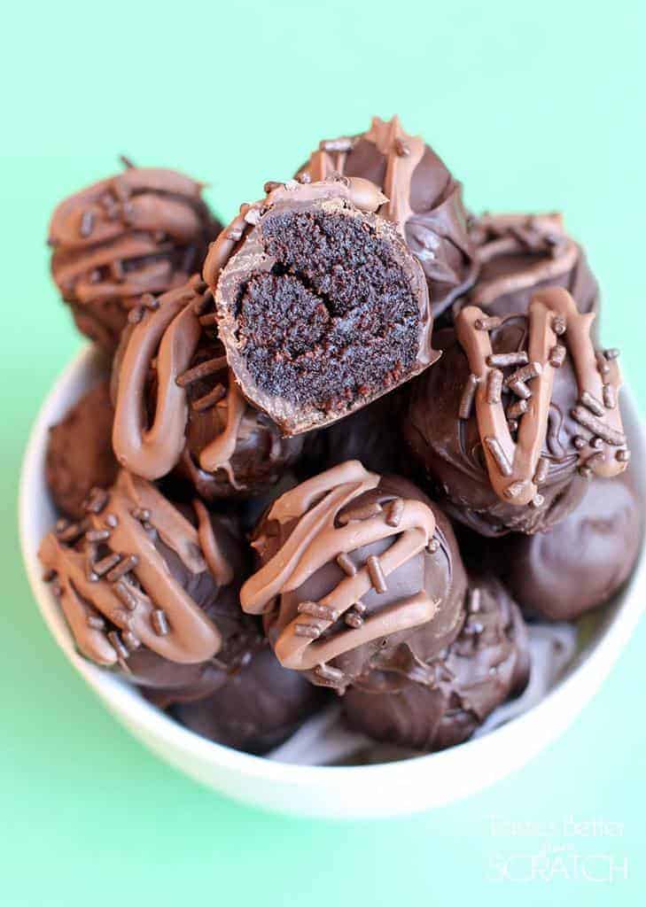 A cup filled with a dozen Brownie Truffles with a bite taken out of the top truffle.