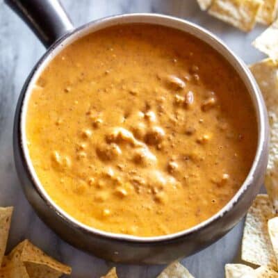 Chili cheese dip in a bowl with tortilla trips on the sides.