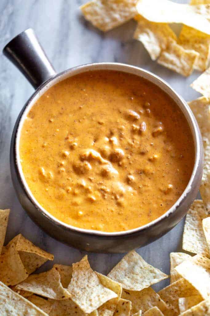 Chili cheese dip in a bowl with tortilla trips on the sides.