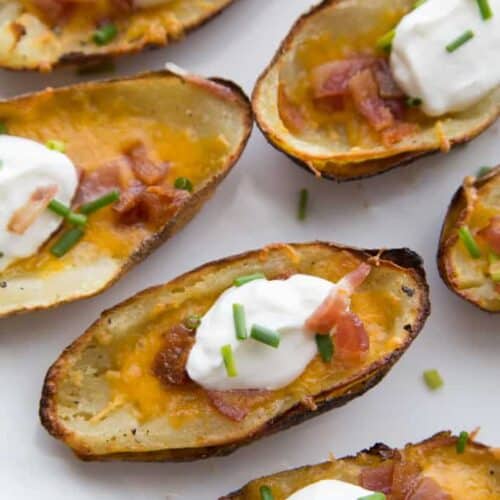 Loaded baked potato skins with cheese, topped with a scoop of sour cream and chives.