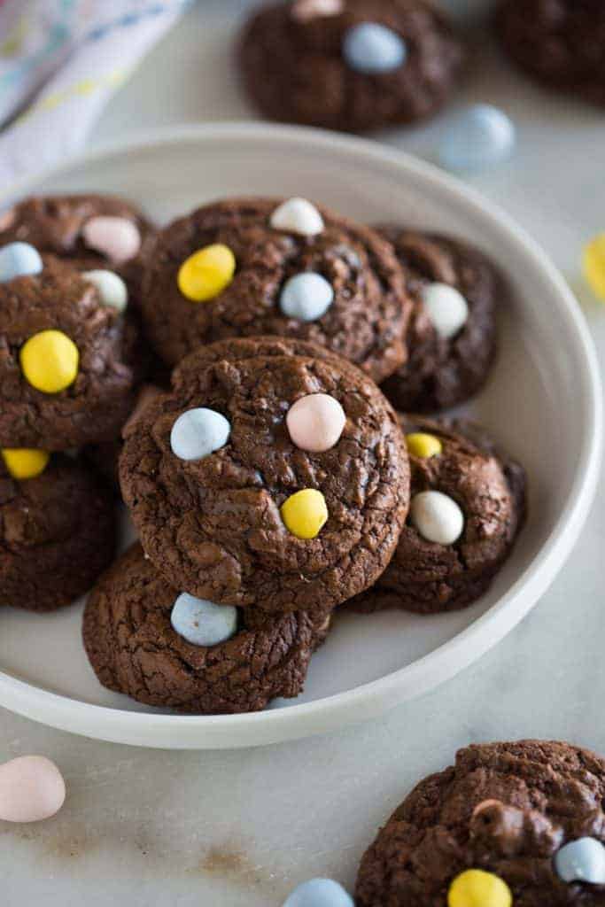 Chocolate cookies with mini cadburry egg pieces, on a white plate.