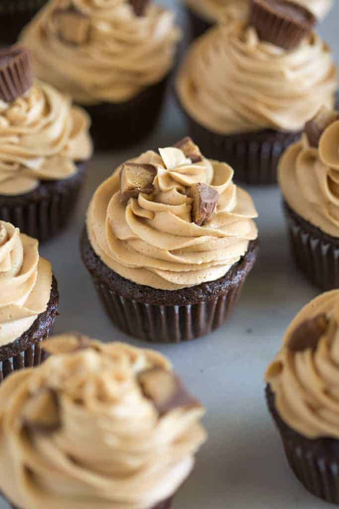 Chocolate cupcakes with peanut butter frosting and chopped Reese's peanut butter cups on top.
