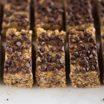 No bake granola bars with chocolate chips on top, on a white board, cut into rectangles.