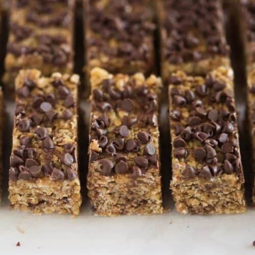 No bake granola bars with chocolate chips on top, on a white board, cut into rectangles.