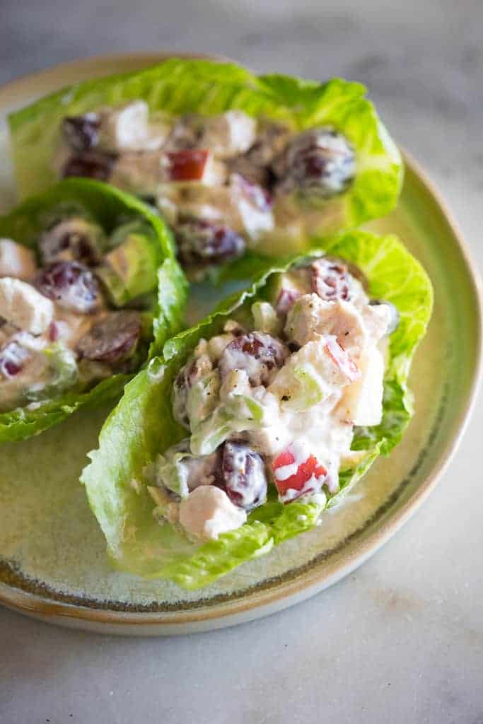 Close-up photo of three chicken salad filled lettuce cups on a plate.