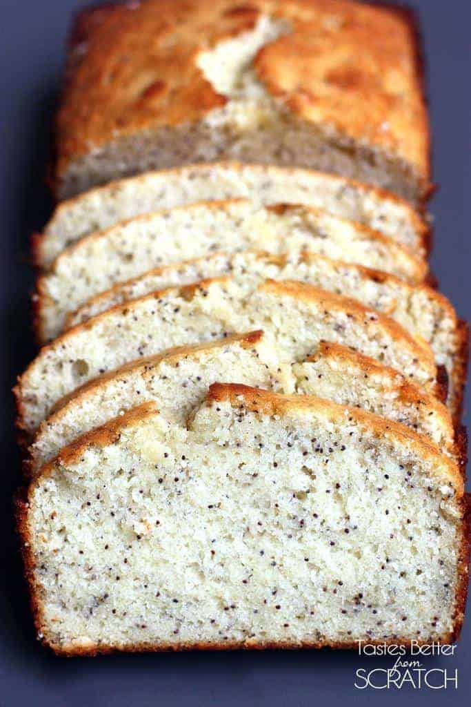 A loaf of Almond Poppy Seed Bread with 6 slices cut away, gently laying on each other.