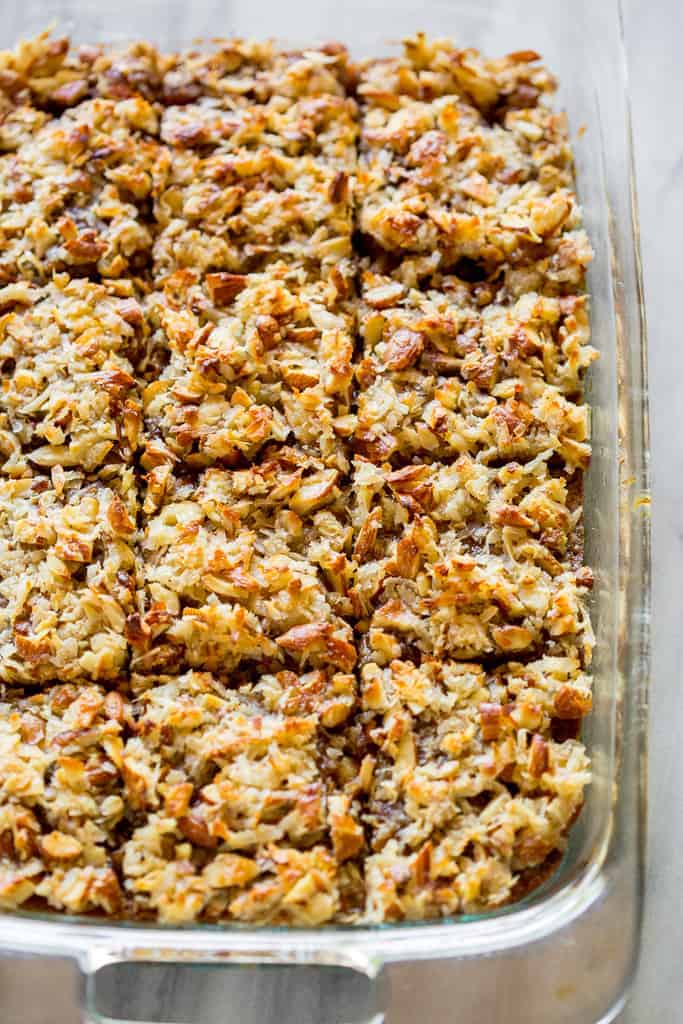 A pan of oatmeal cake with coconut almond topping, cut into squares. 