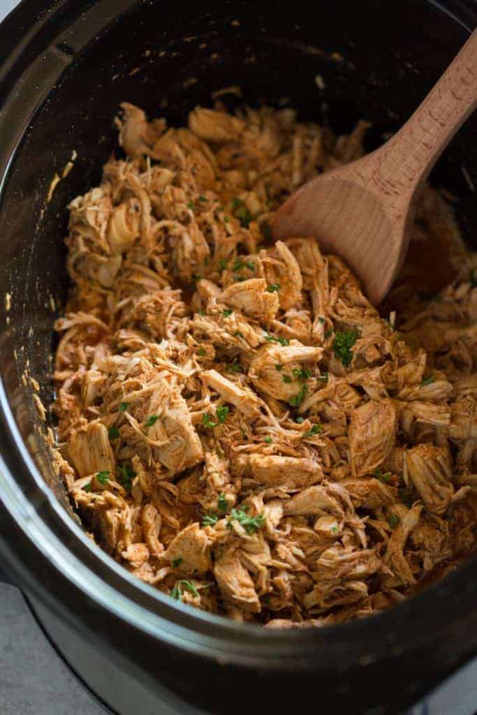 A slow cooker filled with shredded chicken to make chicken tacos.