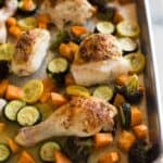 A sheet pan with roasted chicken and vegetables including zucchini, sweet potato and broccoli.