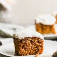 A slice of pumpkin cake with cream cheese frosting, on a plate.