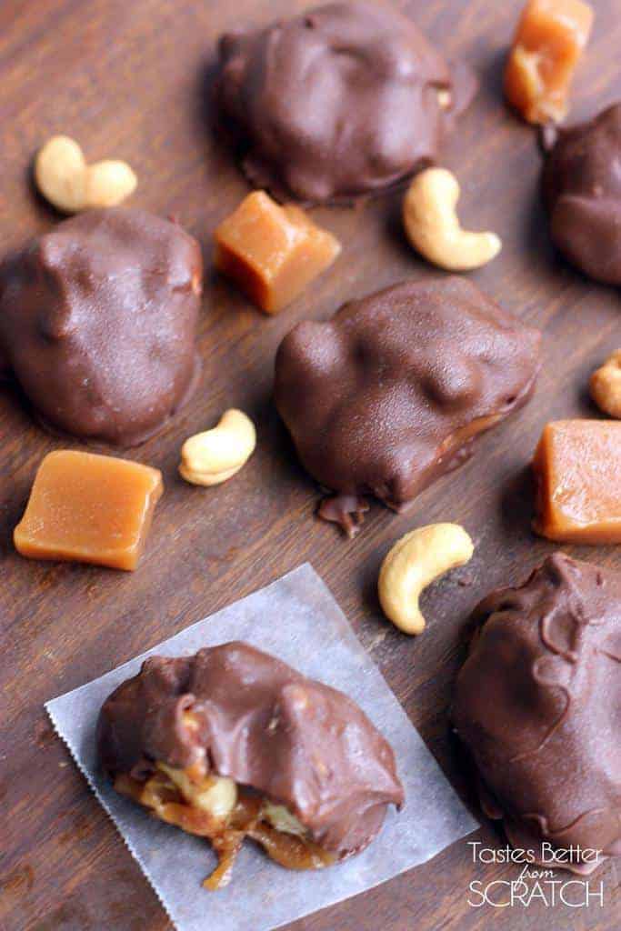 Several Caramel Cashew Clusters scattered on a wooden table with caramel and cashew chunks.