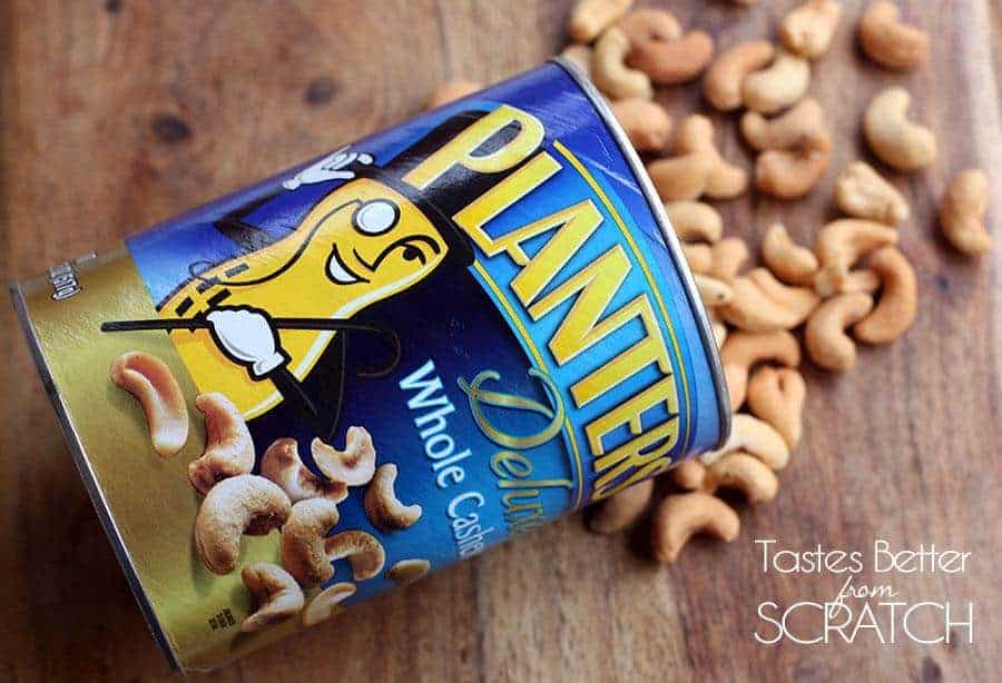 A canister of Planters peanuts, laying on its side with peanuts spilling out.